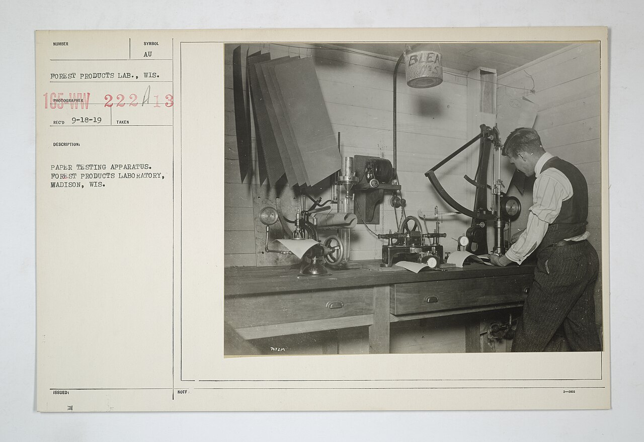 Historical paper-testing laboratory scene used as a charge-demand measurement context photograph