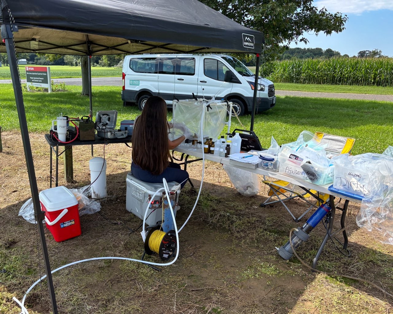 USGS scientist collects groundwater samples inside a protective field sampling chamber